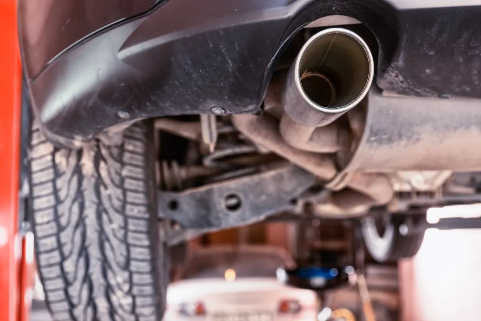 A car's exhaust pipe and rear suspension seen from below on a lift