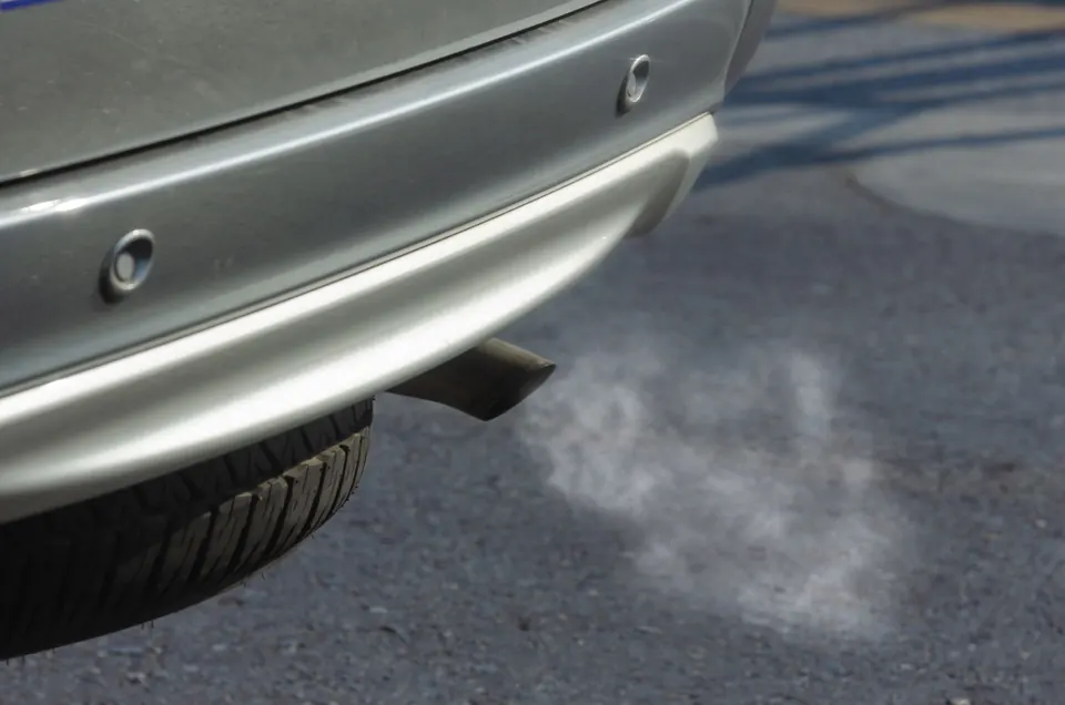 Exhaust vapor leaving a car's tailpipe over the pavement