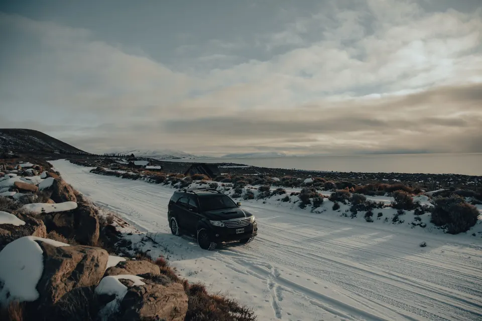 A dark SUV on a snowy, rocky road