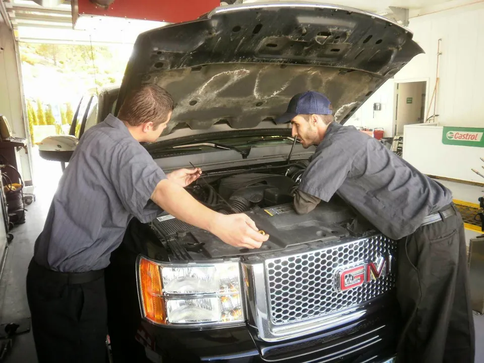 Two Xpress technicians checking under the hood of a pickup in the bay